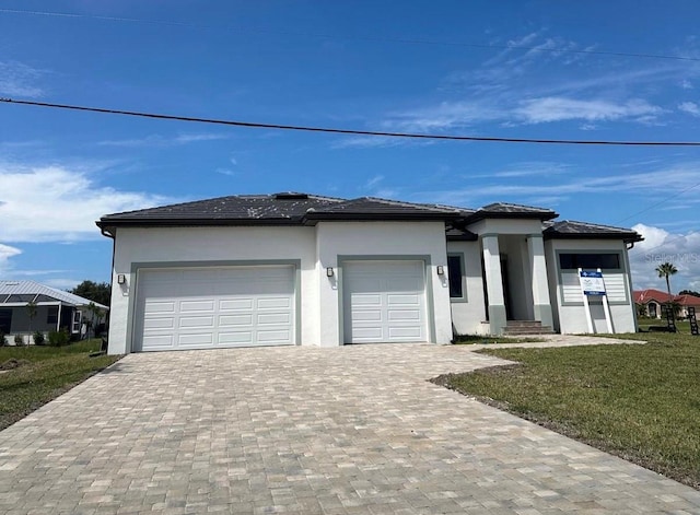17315 Cape Horn Blvd, Punta Gorda, FL 33955 - prairie-style home with a front lawn, stucco siding, decorative driveway, and an attached garage