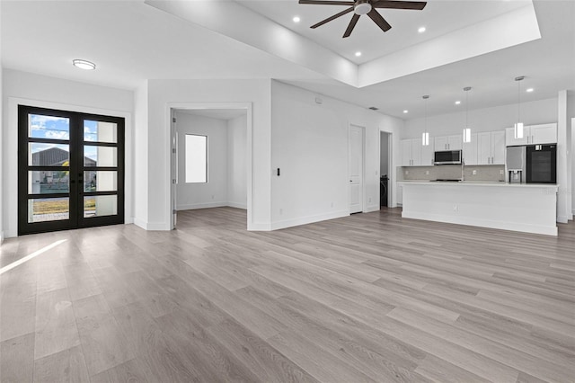 unfurnished living room with ceiling fan, french doors, and light hardwood / wood-style floors