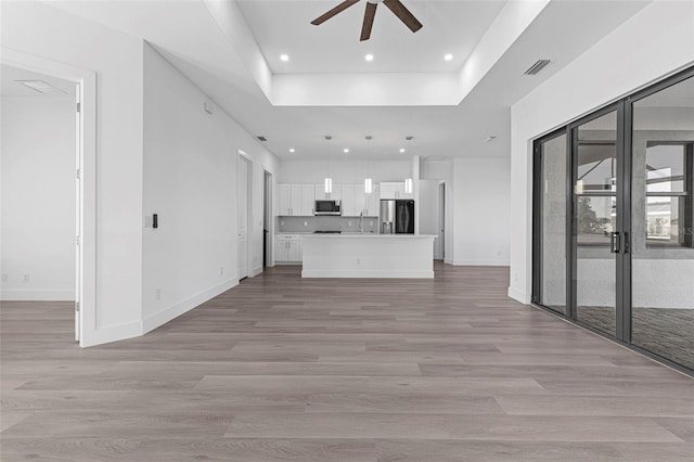 unfurnished living room featuring ceiling fan, french doors, sink, and light hardwood / wood-style flooring