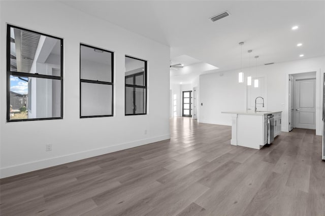 unfurnished living room with light hardwood / wood-style floors, ceiling fan, and sink