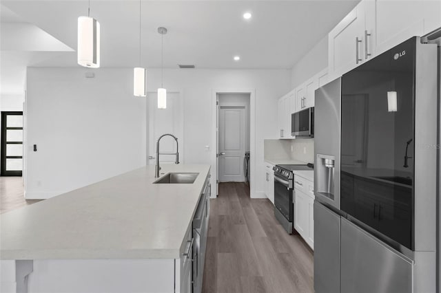 kitchen with white cabinets, appliances with stainless steel finishes, an island with sink, and sink