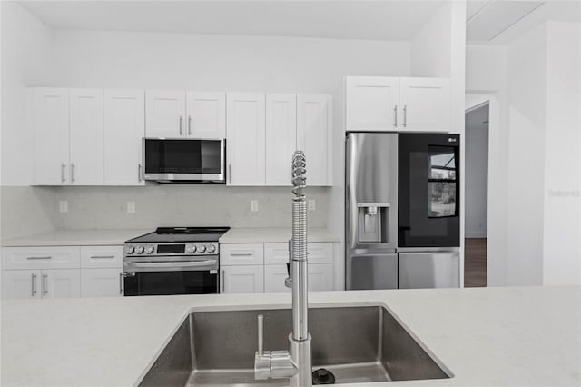 kitchen with white cabinets, backsplash, and stainless steel appliances