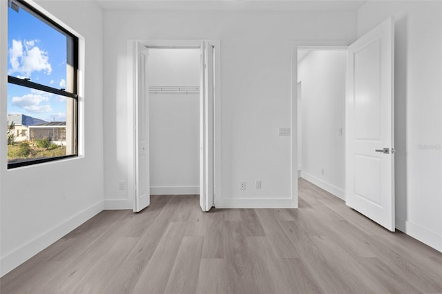 unfurnished bedroom with light wood-type flooring and a closet