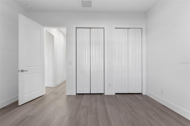 unfurnished bedroom featuring light hardwood / wood-style flooring and two closets