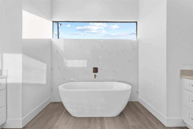 bathroom with hardwood / wood-style floors, vanity, and a bath