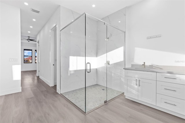 bathroom with ceiling fan, vanity, wood-type flooring, and walk in shower