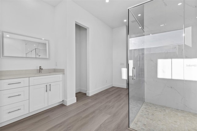 bathroom with hardwood / wood-style floors, vanity, and a shower with door