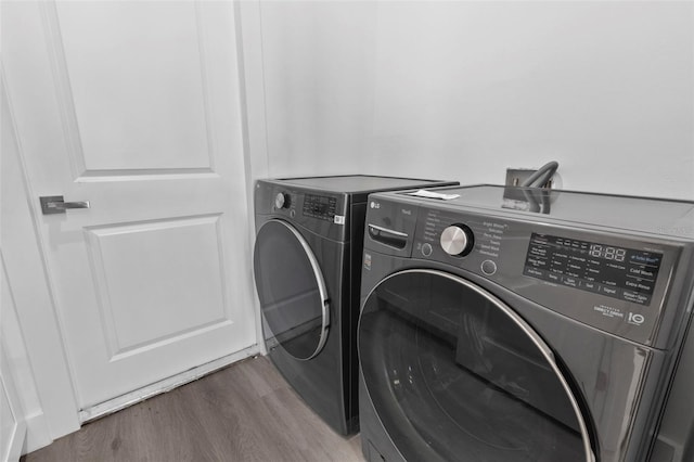 clothes washing area with hardwood / wood-style flooring and washing machine and clothes dryer