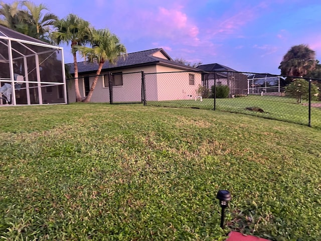 yard at dusk featuring a lanai