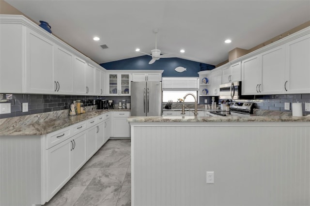 kitchen featuring appliances with stainless steel finishes, white cabinetry, sink, and vaulted ceiling