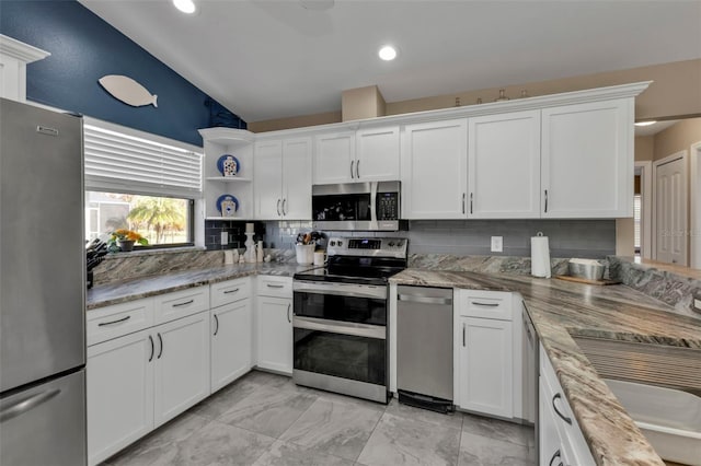 kitchen featuring appliances with stainless steel finishes, white cabinetry, light stone countertops, and backsplash