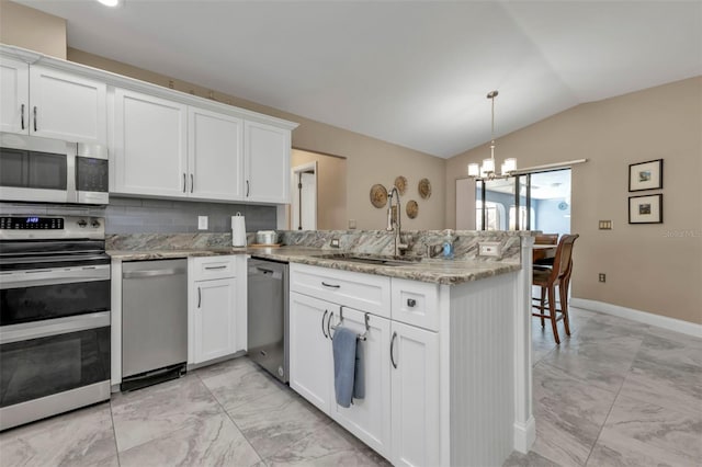 kitchen featuring appliances with stainless steel finishes, vaulted ceiling, kitchen peninsula, and white cabinets