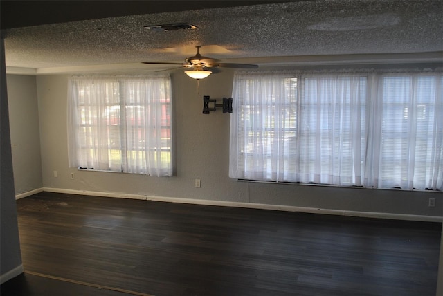 spare room featuring dark wood-type flooring, ceiling fan, and a textured ceiling