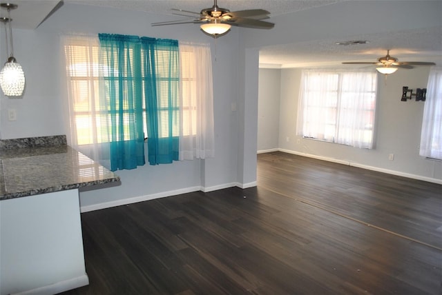 unfurnished living room featuring dark wood-type flooring, ceiling fan, and a textured ceiling