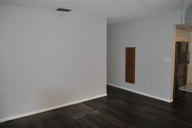 empty room with a textured ceiling and dark hardwood / wood-style flooring