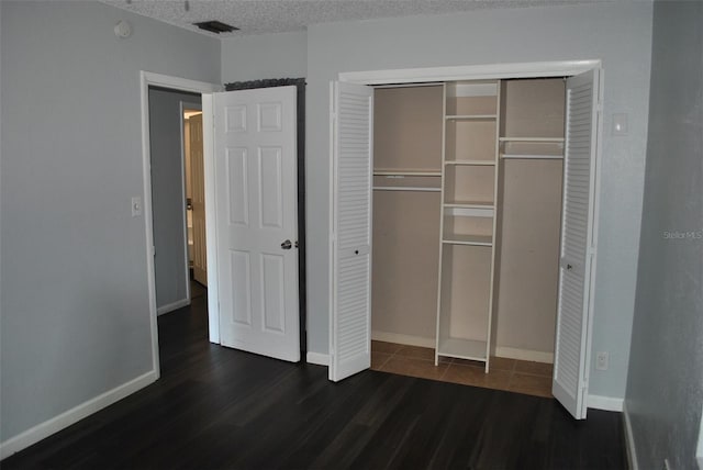 unfurnished bedroom featuring a closet, dark hardwood / wood-style floors, and a textured ceiling