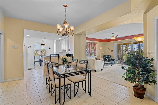 carpeted dining space featuring ceiling fan with notable chandelier and plenty of natural light