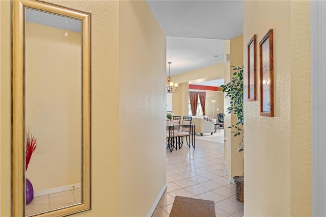 hall with light tile patterned flooring and an inviting chandelier