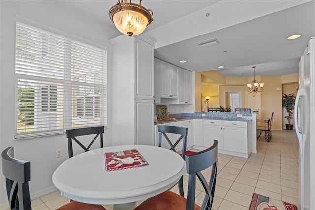 tiled dining space featuring a notable chandelier and sink