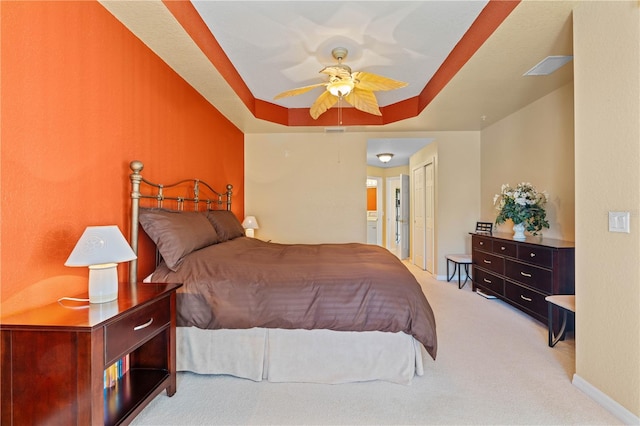 carpeted bedroom with connected bathroom, a tray ceiling, a closet, and ceiling fan