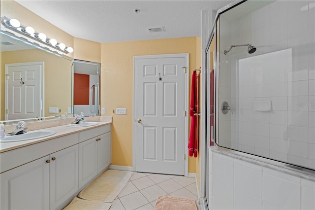 bathroom featuring vanity, tile patterned floors, a textured ceiling, and an enclosed shower