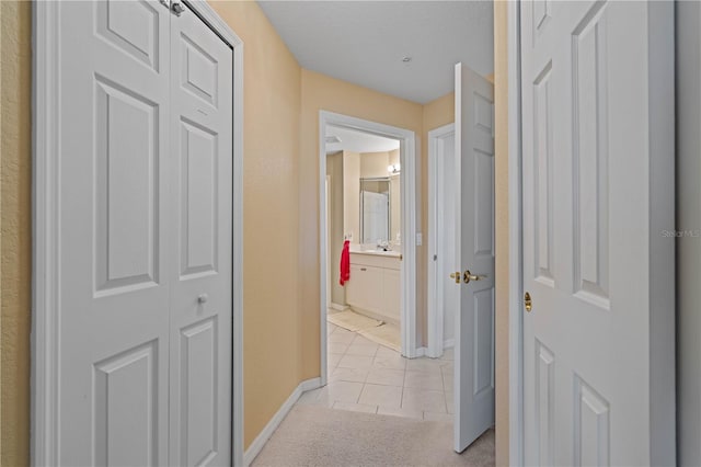 corridor featuring sink and light colored carpet