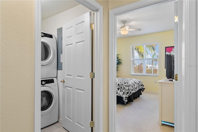 washroom featuring light carpet, stacked washer and clothes dryer, and ceiling fan