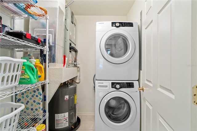 laundry room with light tile patterned flooring, electric water heater, and stacked washing maching and dryer