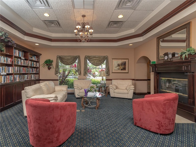 living room with crown molding, carpet flooring, a notable chandelier, and a tray ceiling