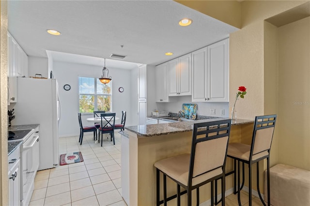 kitchen featuring white appliances, white cabinetry, a breakfast bar area, and kitchen peninsula