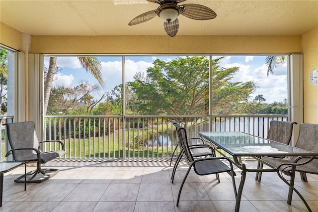 sunroom / solarium featuring a water view, ceiling fan, and a healthy amount of sunlight