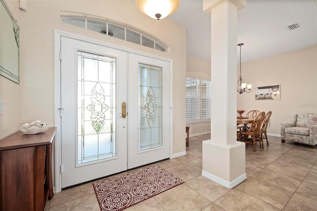 entryway featuring light tile patterned floors, ornate columns, french doors, and an inviting chandelier