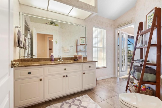 bathroom featuring toilet, tile patterned flooring, vaulted ceiling, and vanity