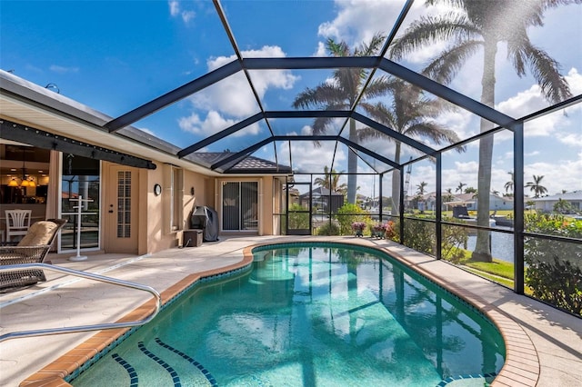 view of swimming pool with a lanai, a water view, and a patio