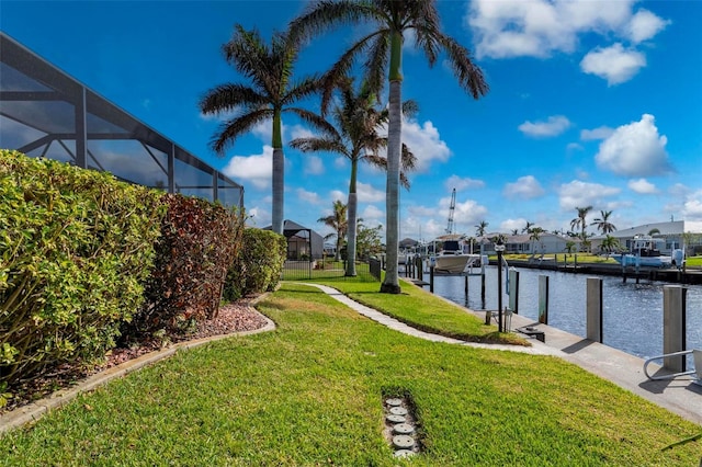 dock area with a lawn, a water view, and glass enclosure