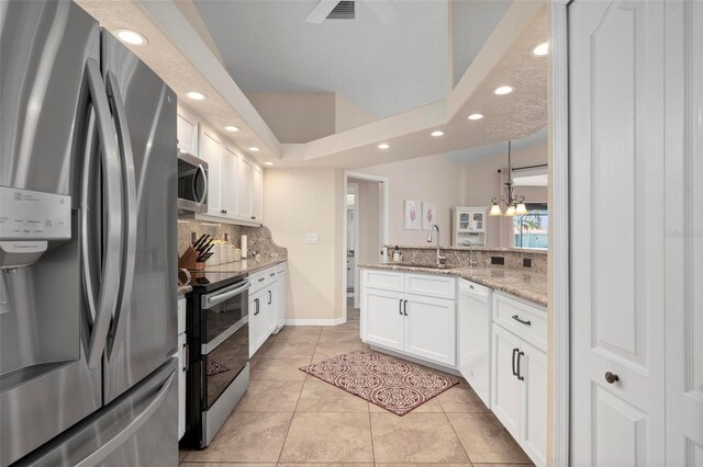 kitchen with pendant lighting, white cabinets, stainless steel appliances, light stone counters, and light tile patterned floors