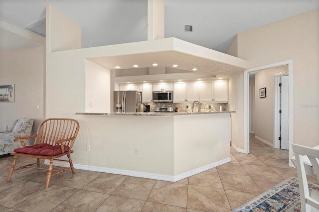 kitchen with light stone countertops, white cabinetry, appliances with stainless steel finishes, and kitchen peninsula