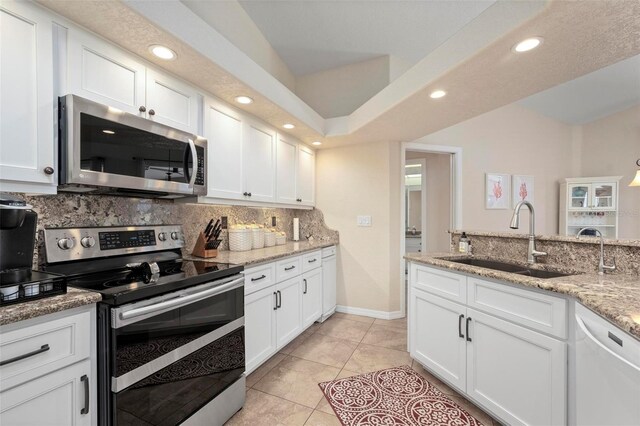 kitchen with sink, white cabinets, light stone countertops, and appliances with stainless steel finishes