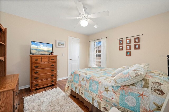 bedroom with wood finished floors, a ceiling fan, and baseboards