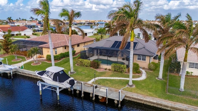 rear view of house with glass enclosure, a lawn, a water view, and boat lift