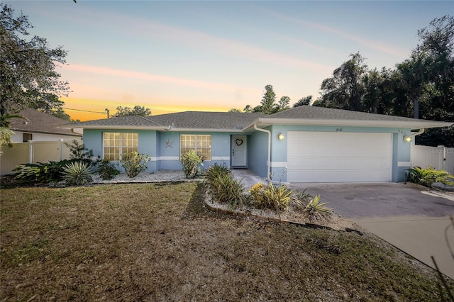 ranch-style house with a garage and a lawn