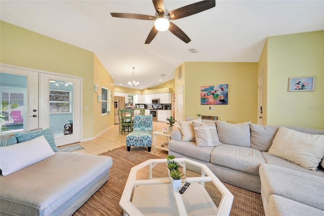 living room with ceiling fan with notable chandelier, light tile patterned flooring, french doors, and vaulted ceiling