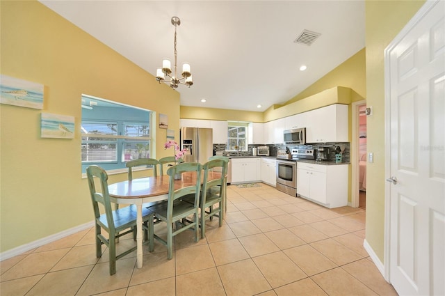 tiled dining room with sink, vaulted ceiling, a healthy amount of sunlight, and a notable chandelier