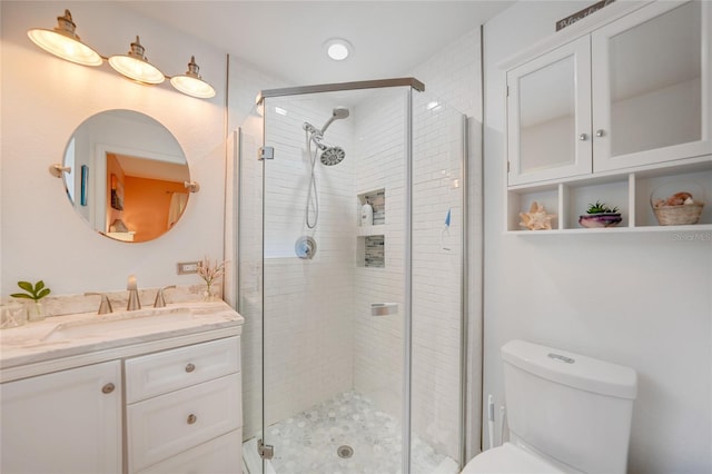 bathroom featuring vanity, toilet, and a shower with shower door