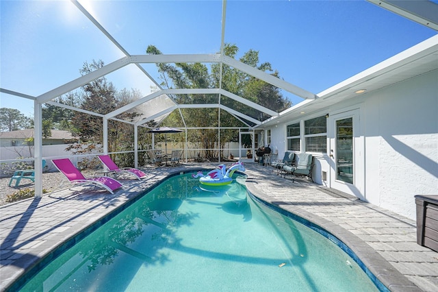 view of pool featuring glass enclosure and a patio area