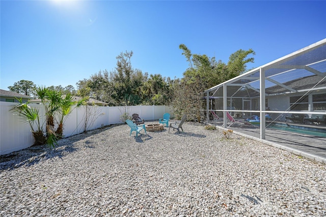 view of yard featuring a fenced in pool, glass enclosure, and a fire pit