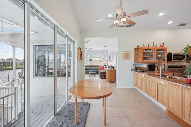 kitchen featuring light tile patterned floors, ceiling fan, appliances with stainless steel finishes, light stone countertops, and sink