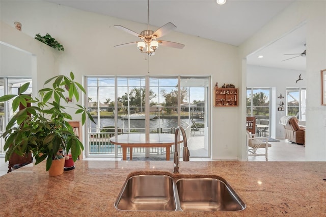 kitchen with sink, plenty of natural light, a water view, and vaulted ceiling