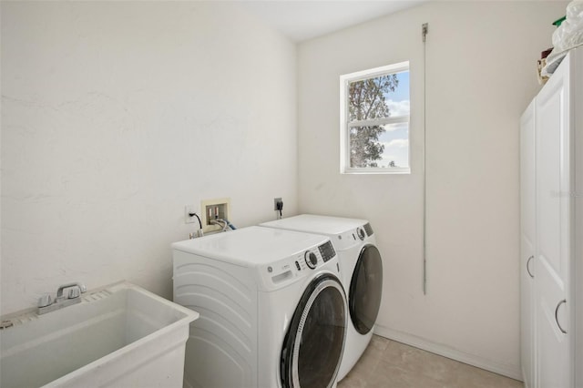 laundry area with cabinets, sink, washer and clothes dryer, and light tile patterned floors