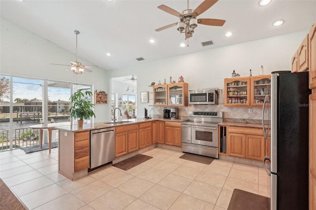 kitchen featuring kitchen peninsula, decorative backsplash, sink, stainless steel appliances, and light tile patterned floors